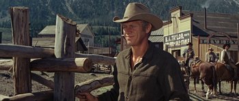 Movie still from “Nevada Smith” (1966), directed by Henry Hathaway – A man wearing a cowboy hat standing next to a wooden fence; Medium shot, Low angle
