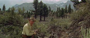 Movie still from “Nevada Smith” (1966), directed by Henry Hathaway – A man in a cowboy hat is in the woods; Wide shot, Low angle