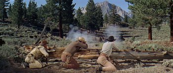 Movie still from “Nevada Smith” (1966), directed by Henry Hathaway – Two men in cowboy hats are aiming guns at trees; Wide shot, Low angle