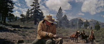 Movie still from “Nevada Smith” (1966), directed by Henry Hathaway – A man in a cowboy hat is holding a rifle; Wide shot, Low angle