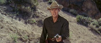 Movie still from “Nevada Smith” (1966), directed by Henry Hathaway – A man holding a gun while wearing a cowboy hat; Medium shot, Low angle