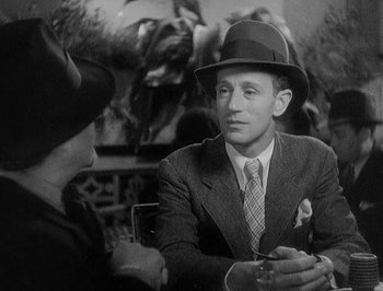 Movie still from “Of Human Bondage” (1934), directed by John Cromwell – A man in a suit and hat talking to a woman; Close Up shot, Over the shoulder angle