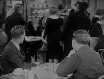 Movie still from “Of Human Bondage” (1934), directed by John Cromwell – A group of men sitting at a table in a room; Medium shot, Over the shoulder angle