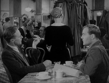 Movie still from “Of Human Bondage” (1934), directed by John Cromwell – Two men sitting at a table in front of a woman; Medium shot, Over the shoulder angle