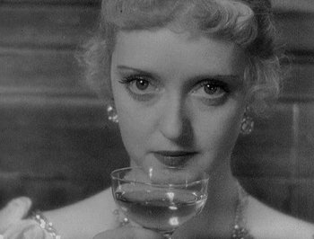 Movie still from “Of Human Bondage” (1934), directed by John Cromwell – A black - and - white photo of a woman holding a wine glass; Close Up shot, High angle