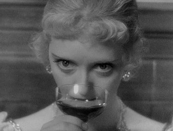 Movie still from “Of Human Bondage” (1934), directed by John Cromwell – A black and white photo of a woman holding a glass of wine; Close Up shot, High angle