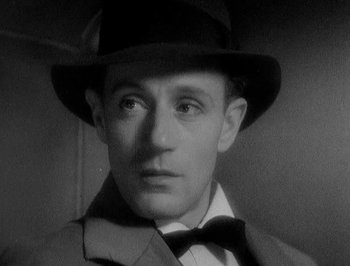 Movie still from “Of Human Bondage” (1934), directed by John Cromwell – A man wearing a hat and a suit; Close Up shot, High angle
