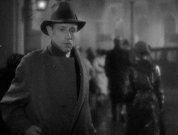 Movie still from “Of Human Bondage” (1934), directed by John Cromwell – A black and white photo of a man wearing a hat; Close Up shot, Over the shoulder angle