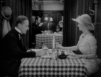 Movie still from “Of Human Bondage” (1934), directed by John Cromwell – A man and a woman sitting at a dinner table; Medium shot, High angle
