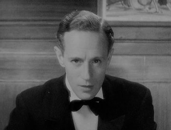 Movie still from “Of Human Bondage” (1934), directed by John Cromwell – A man wearing a suit and bow tie; Close Up shot, High angle