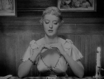 Movie still from “Of Human Bondage” (1934), directed by John Cromwell – A black and white photo of a woman sitting at a table; Medium shot, High angle