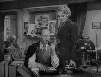 Movie still from “Of Human Bondage” (1934), directed by John Cromwell – A man and a woman are looking at something on a table; Medium shot, High angle