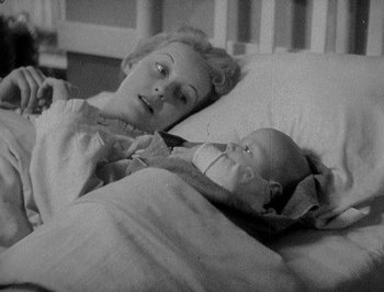 Movie still from “Of Human Bondage” (1934), directed by John Cromwell – An older woman laying in a bed with a baby; Medium shot, Overhead angle