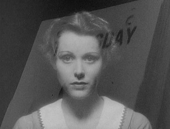 Movie still from “Of Human Bondage” (1934), directed by John Cromwell – A black - and - white photo of a woman in front of a sign; Close Up shot, Low angle