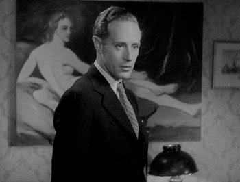 Movie still from “Of Human Bondage” (1934), directed by John Cromwell – A man in a suit standing in front of a painting; Medium shot, Low angle