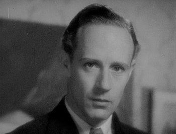 Movie still from “Of Human Bondage” (1934), directed by John Cromwell – An old black and white photo of a man in a suit and tie; Close Up shot, Low angle