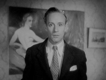 Movie still from “Of Human Bondage” (1934), directed by John Cromwell – A man wearing a suit and tie in front of a painting; Close Up shot, Low angle