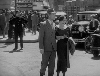 Movie still from “Of Human Bondage” (1934), directed by John Cromwell – A man and a woman standing on the side of the street; Medium shot, High angle