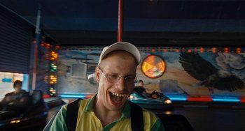 Movie still from “Paradise: Love” (2012), directed by Ulrich Seidl – A man with glasses and a hat is smiling; Close Up shot, High angle