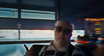 Movie still from “Paradise: Love” (2012), directed by Ulrich Seidl – A man in sunglasses and a striped shirt sitting in front of a window; Close Up shot, Low angle