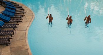 Movie still from “Paradise: Love” (2012), directed by Ulrich Seidl – A couple of men standing in a swimming pool holding poles; Extreme Wide shot, High angle