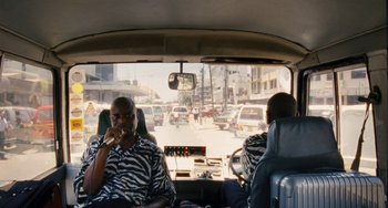 Movie still from “Paradise: Love” (2012), directed by Ulrich Seidl – Two men sitting in the back seat of a bus; Wide shot, High angle