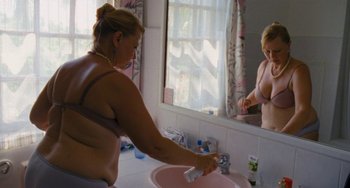 Movie still from “Paradise: Love” (2012), directed by Ulrich Seidl – A woman is washing her hands in the bathroom; Medium shot, Over the shoulder angle