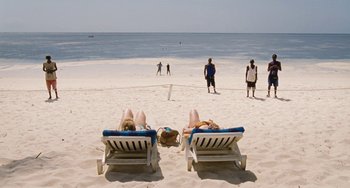Movie still from “Paradise: Love” (2012), directed by Ulrich Seidl – A couple of people laying down on a beach next to the ocean; Extreme Wide shot, High angle