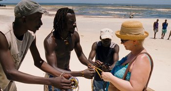 Movie still from “Paradise: Love” (2012), directed by Ulrich Seidl – A group of people standing on top of a sandy beach; Medium shot, High angle