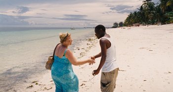 Movie still from “Paradise: Love” (2012), directed by Ulrich Seidl – A man and a woman on the beach shaking hands; Wide shot, High angle