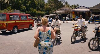 Movie still from “Paradise: Love” (2012), directed by Ulrich Seidl – A woman in a blue and white dress is walking down the street; Wide shot, High angle