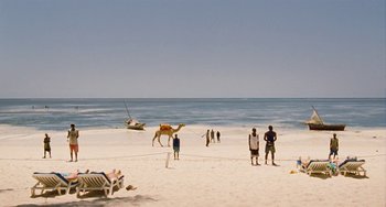 Movie still from “Paradise: Love” (2012), directed by Ulrich Seidl – A group of people standing on top of a sandy beach; Extreme Wide shot, High angle