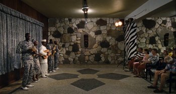 Movie still from “Paradise: Love” (2012), directed by Ulrich Seidl – A group of people standing in front of a stone wall; Extreme Wide shot, High angle