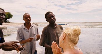 Movie still from “Paradise: Love” (2012), directed by Ulrich Seidl – A group of people standing on top of a sandy beach; Medium shot, Over the shoulder angle