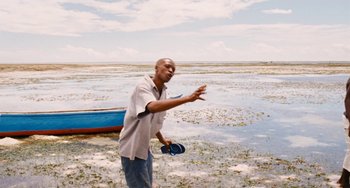 Movie still from “Paradise: Love” (2012), directed by Ulrich Seidl – A man standing on a beach near a body of water; Medium shot, Over the shoulder angle