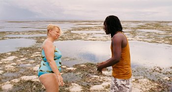 Movie still from “Paradise: Love” (2012), directed by Ulrich Seidl – A man and a woman standing on a beach; Wide shot, Over the shoulder angle