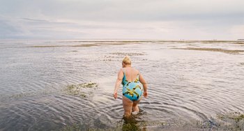 Movie still from “Paradise: Love” (2012), directed by Ulrich Seidl – A woman in a bathing suit wading in shallow water; Wide shot, High angle