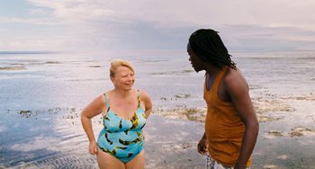 Movie still from “Paradise: Love” (2012), directed by Ulrich Seidl – Two people standing on the beach talking to each other; Medium shot, High angle