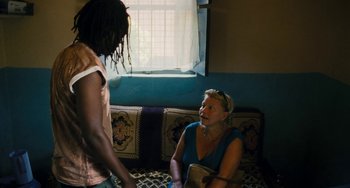 Movie still from “Paradise: Love” (2012), directed by Ulrich Seidl – Two people talking on a couch in a living room; Medium shot, Over the shoulder angle