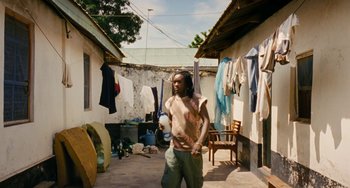 Movie still from “Paradise: Love” (2012), directed by Ulrich Seidl – A man standing in a yard with a lot of clothes hanging on a line; Wide shot, Low angle