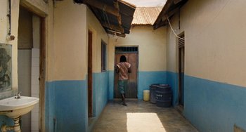 Movie still from “Paradise: Love” (2012), directed by Ulrich Seidl – A person walking down a hallway in a building; Wide shot, High angle