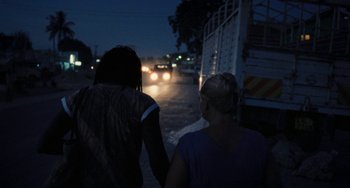 Movie still from “Paradise: Love” (2012), directed by Ulrich Seidl – Two women are holding hands on the side of the road; Wide shot, Over the shoulder angle
