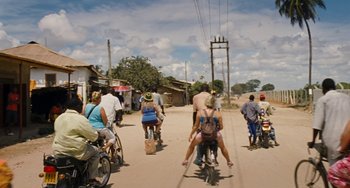 Movie still from “Paradise: Love” (2012), directed by Ulrich Seidl – A group of people riding bikes down a dirt road; Wide shot, High angle