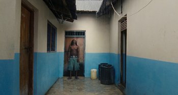 Movie still from “Paradise: Love” (2012), directed by Ulrich Seidl – A man standing in a doorway of a building; Wide shot, High angle