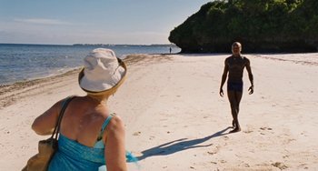 Movie still from “Paradise: Love” (2012), directed by Ulrich Seidl – A man and a woman walking on a sandy beach; Wide shot, Over the shoulder angle