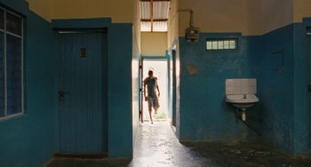 Movie still from “Paradise: Love” (2012), directed by Ulrich Seidl – A man walking through a hallway in a building; Wide shot, Low angle