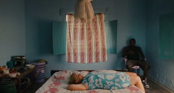 Movie still from “Paradise: Love” (2012), directed by Ulrich Seidl – A woman laying on a bed in front of a window; Wide shot, High angle