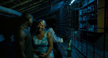 Movie still from “Paradise: Love” (2012), directed by Ulrich Seidl – A woman sitting next to a bottle of wine; Medium shot, High angle