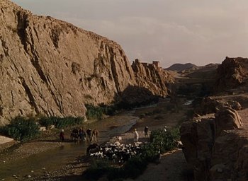 Movie still from “Samson and Delilah” (1949), directed by Cecil B. DeMille – A group of people standing on top of a dirt road; Extreme Wide shot, High angle