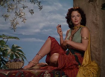 Movie still from “Samson and Delilah” (1949), directed by Cecil B. DeMille – A woman sitting on the ground holding a cell phone; Medium shot, Low angle